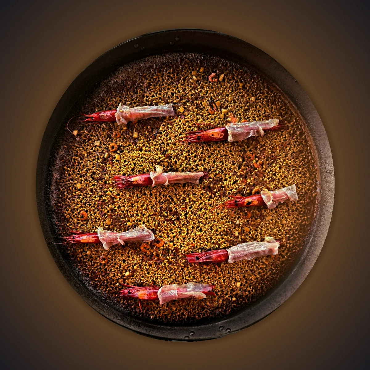 Carabinero prawn rice with Iberian pork jowl seen from above, in its iron paella pan